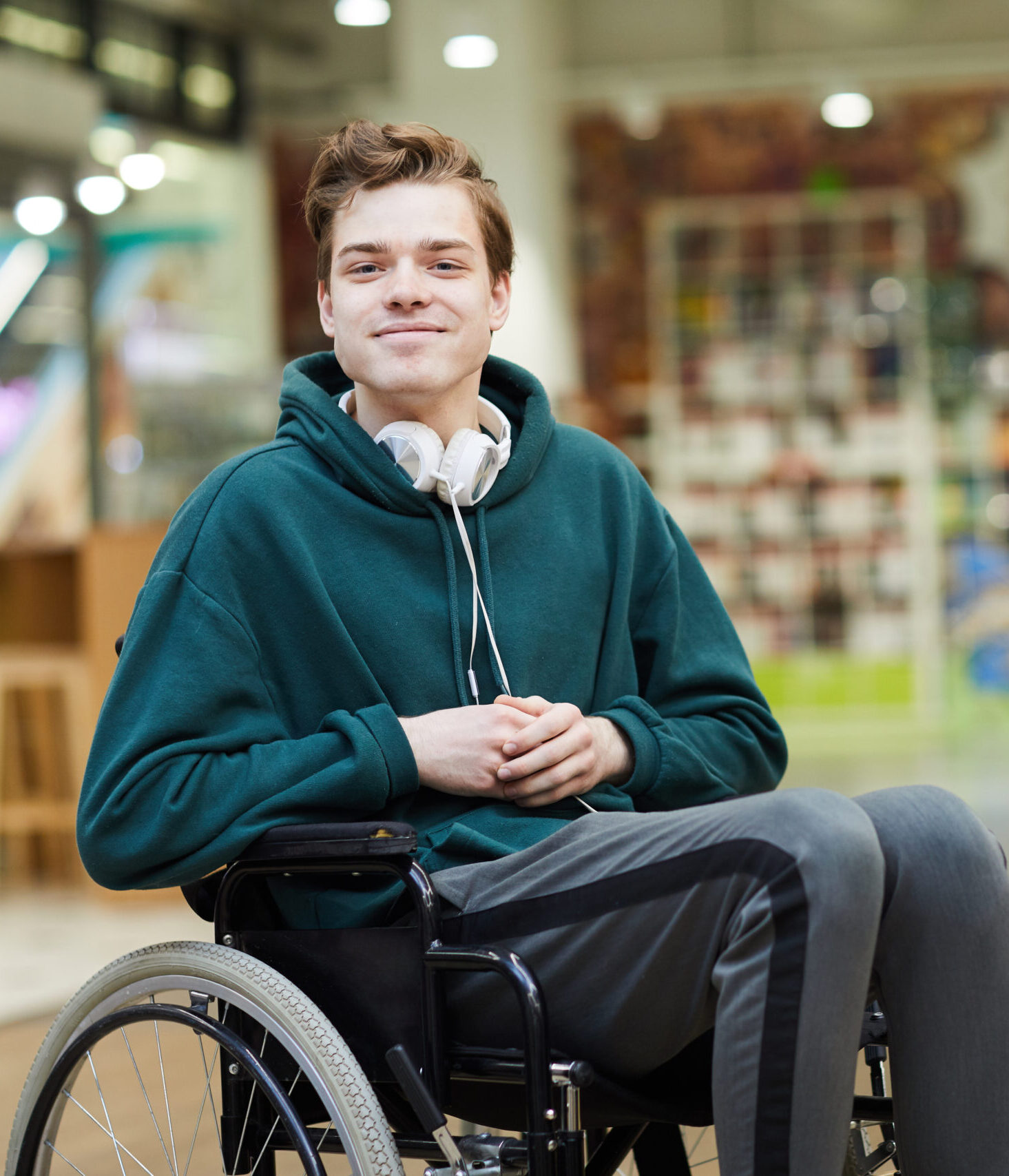 Uśmiechnięty niepełnosprawny student na wózku inwalidzkim.
